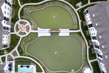 A bird's eye view of a park with a large pond and a building in the middle.
